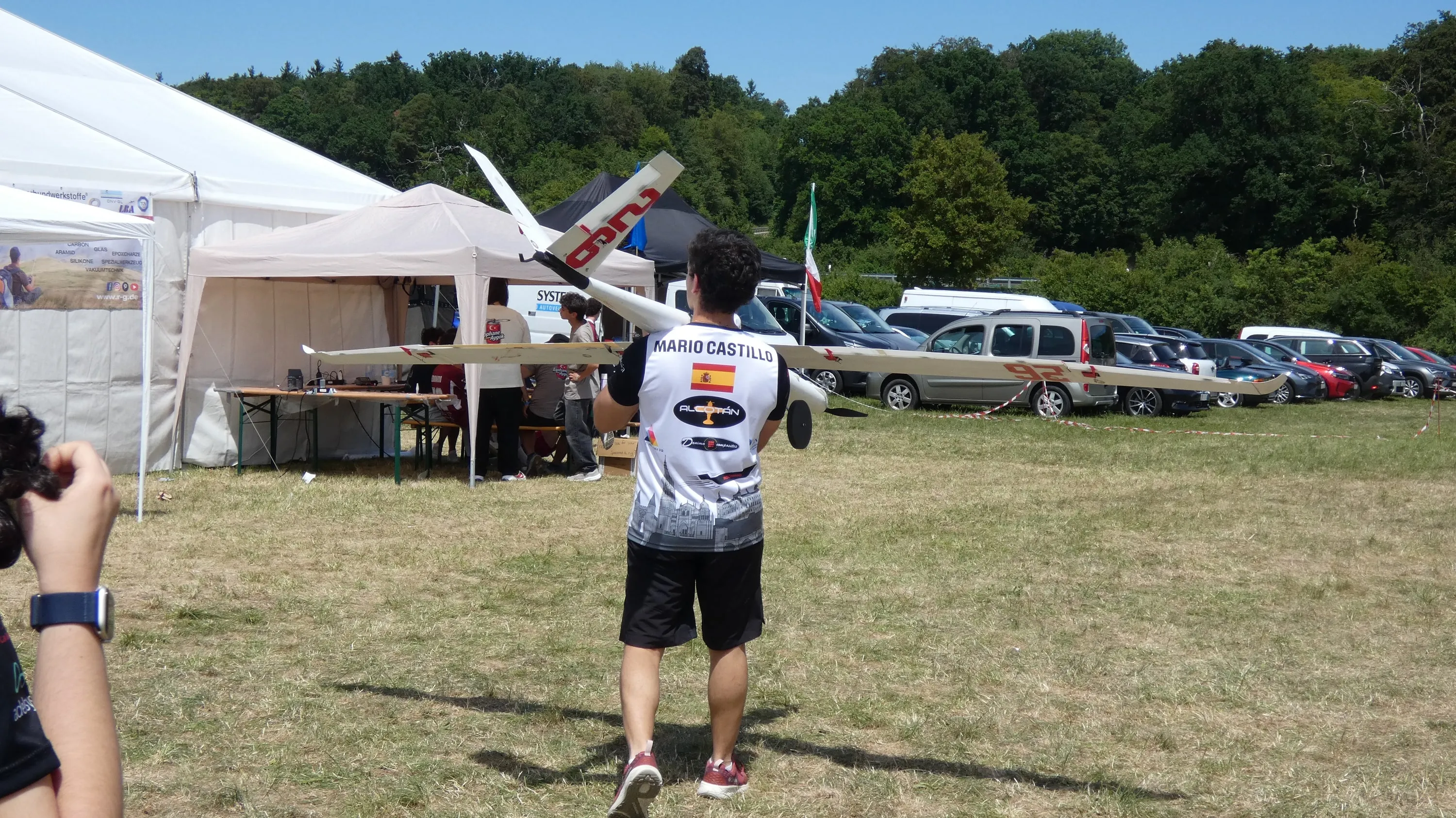 Un miembro, de espaldas, lleva un ala por el campamento de la competición.