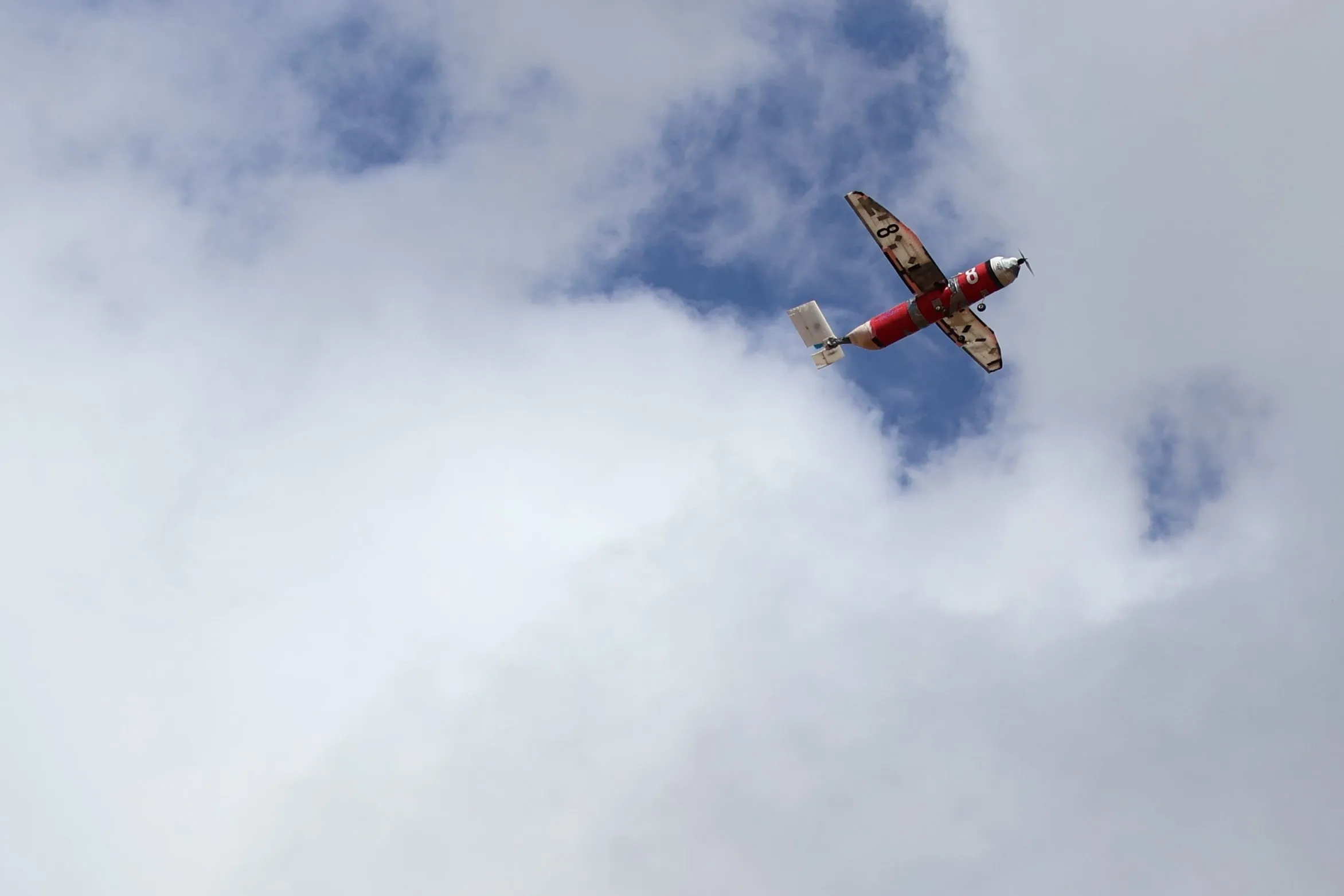 El Insomnio en vuelo entre nubes, con el fuselaje rojo y el número 8 en el ala
